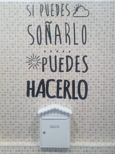 Buzón blanco bajo el mensaje “Si puedes soñarlo, puedes hacerlo” en azulejo claro.